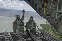 Loadmaster from 36th Airlift Squadron waving to Micronesian natives after dropping care packages during Operation Christmas Drop 2016
