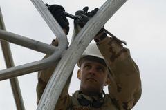 Senior Airman Adam Stadler bolting a connector beam to a temporary shelter frame