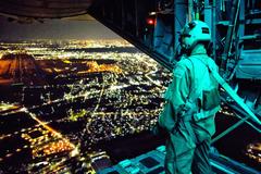 U.S. Air Force loadmaster observing drop zone from a C-130 Hercules over Yokota Air Base