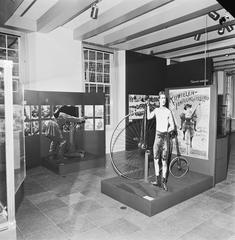 Black and white photo of a bicycle and a poster at the Amsterdam Historical Museum
