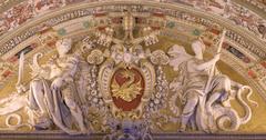 Stucco relief of papal coat of arms with golden dragon on red shield, papal tiara and crossed keys, flanked by allegorical warrior figures at Vatican Museums