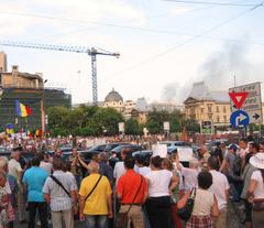 Rally for President Băsescu's impeachment in University Square Bucharest with factory fire smoke in background
