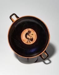 Attic black-figure kylix cup with Dionysos and satyrs decoration and caricature of black slave in tondo