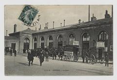 Postcard of Rennes train station showing the station building and part of the passenger courtyard with two carriages