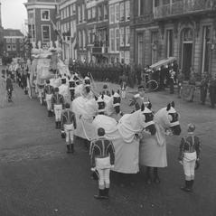 Black and white photo of the funeral procession of Princess Wilhelmina, with the coffin being carried from Paleis Lange Voorhout on December 8, 1962