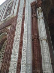 Qutb Minar towering in red and buff sandstone under a clear sky