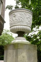 Stone vase sculpture on a pedestal in a garden setting