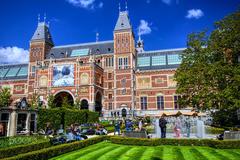 View of the garden at the Rijksmuseum Amsterdam with water and traditional buildings under a blue sky