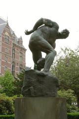 Statue of a Titan holding a stone in its hand in a garden