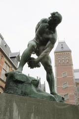 Statue of a Titan holding a stone in his hand in a garden
