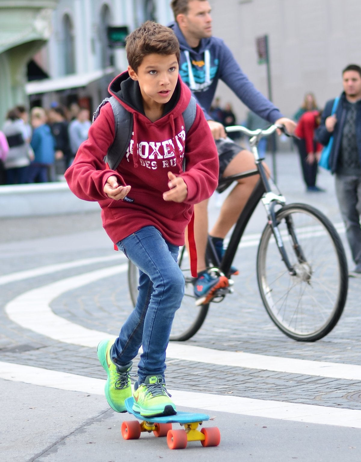 Kid in red hoodie riding blue Penny board skateboarding in Ljubljana