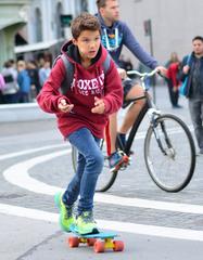 Kid in red hoodie riding blue Penny board skateboarding in Ljubljana