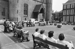People sunbathing and sitting on benches at the Binnenhof square in The Hague during a sunny day in June 1975