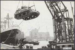 Black and white photo of merchant ships, harbor tanks at Rotterdam port in 1951