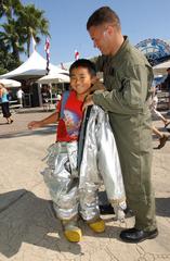 Lance Cpl. Zachary J. Cecil from Marine Corps Air Station Miramar letting a child named Gerry try on bunker gear at SeaWorld's Sea to Shining Sea music festival