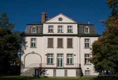 Backside view of Weltkulturen Museum in Frankfurt, Germany, with green lawn and trees under blue sky