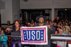 Musical group The War and Treaty holding a USO flag at Aviano Air Base concert