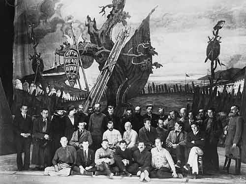 Theater troupe posing in front of the scenic backdrop for a stage production of King Lear