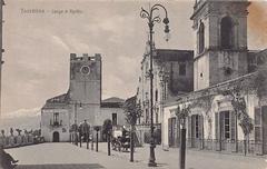 Panoramic view of Piazza 9 Aprile with historic buildings and blue sky