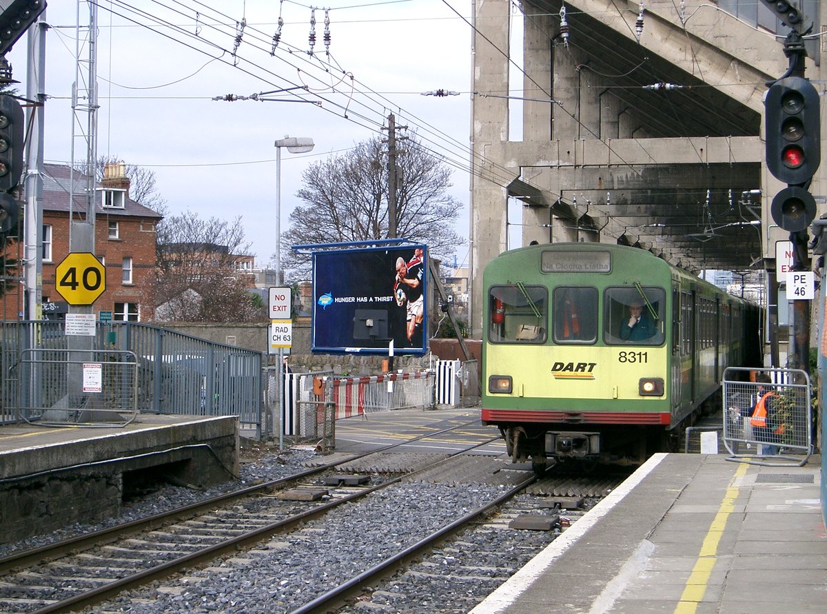 IÉ 8100 Class DART train passing under Lansdowne Road Rugby Football Stadium over level crossing entering Lansdowne Road station