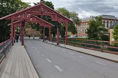 Gamle Bybro old wooden bridge in Trondheim over Nidelva river with cityscape and blue sky