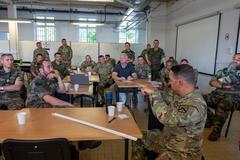 Military personnel conducting joint air-ground coordination training in a command center with multiple computer screens
