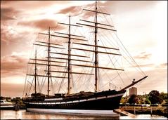 The Moshulu tall ship docked with a partly-sunken work float under the bow in maintenance