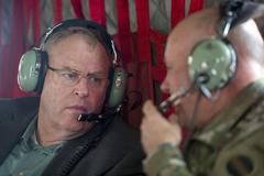 Deputy Secretary of Defense Bob Work speaking with Lt. Gen. Pat Donahue via headset aboard a CH-47 Chinook helicopter