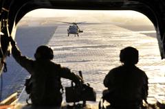 Two U.S. Army Sergeants keeping watch aboard a CH-47F Chinook helicopter preparing for takeoff at Kandahar Airfield