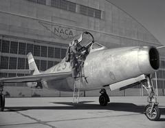 Ames Pilot George Cooper posing with F-84F airplane on ramp, 1955