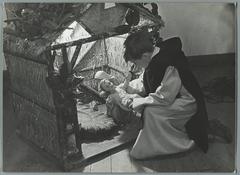 Christmas scene in the Benedictine monastery school at Sint Andries abbey, Belgium in 1935, boy in religious robe placing baby Jesus in nativity scene