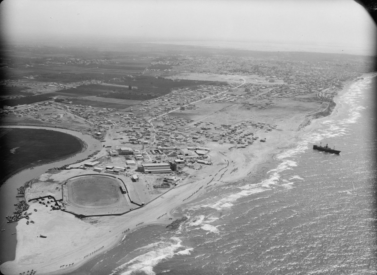 Aerial view of Tel Aviv, Yarkon River, and Levant Fair with stranded ship Pollux visible in sea