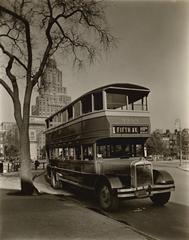 Double-decker bus parked by tree in Washington Square with arch and 1 Fifth Avenue apartments visible