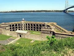 Battery Weed lighthouse with Brooklyn skyline in the background on a clear sunny day