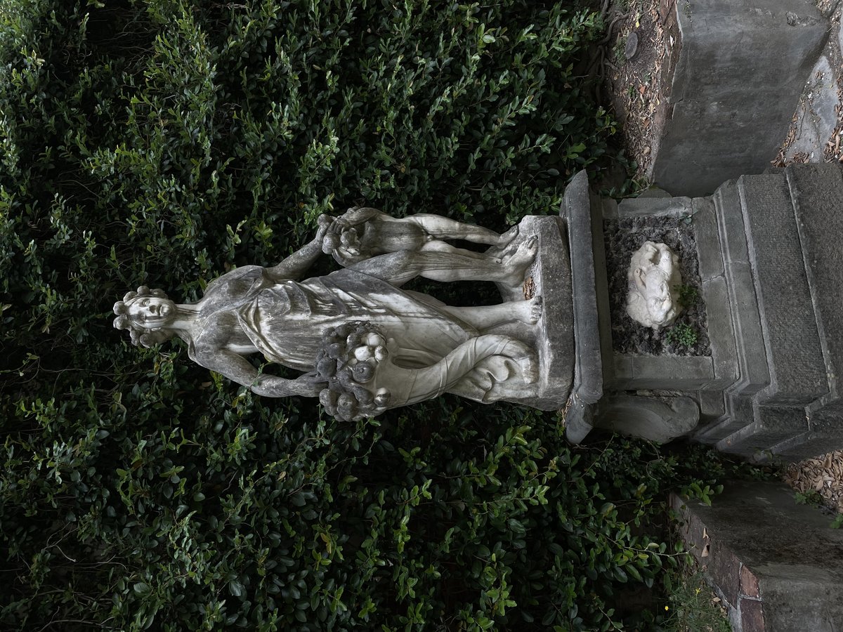 Weathered statue of a woman with peeling paint in the courtyard of Palazzo Mansi, Lucca