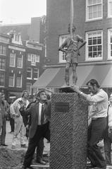 Black and white photograph of the Lieverdje statue being placed back on its pedestal at Spui square in Amsterdam