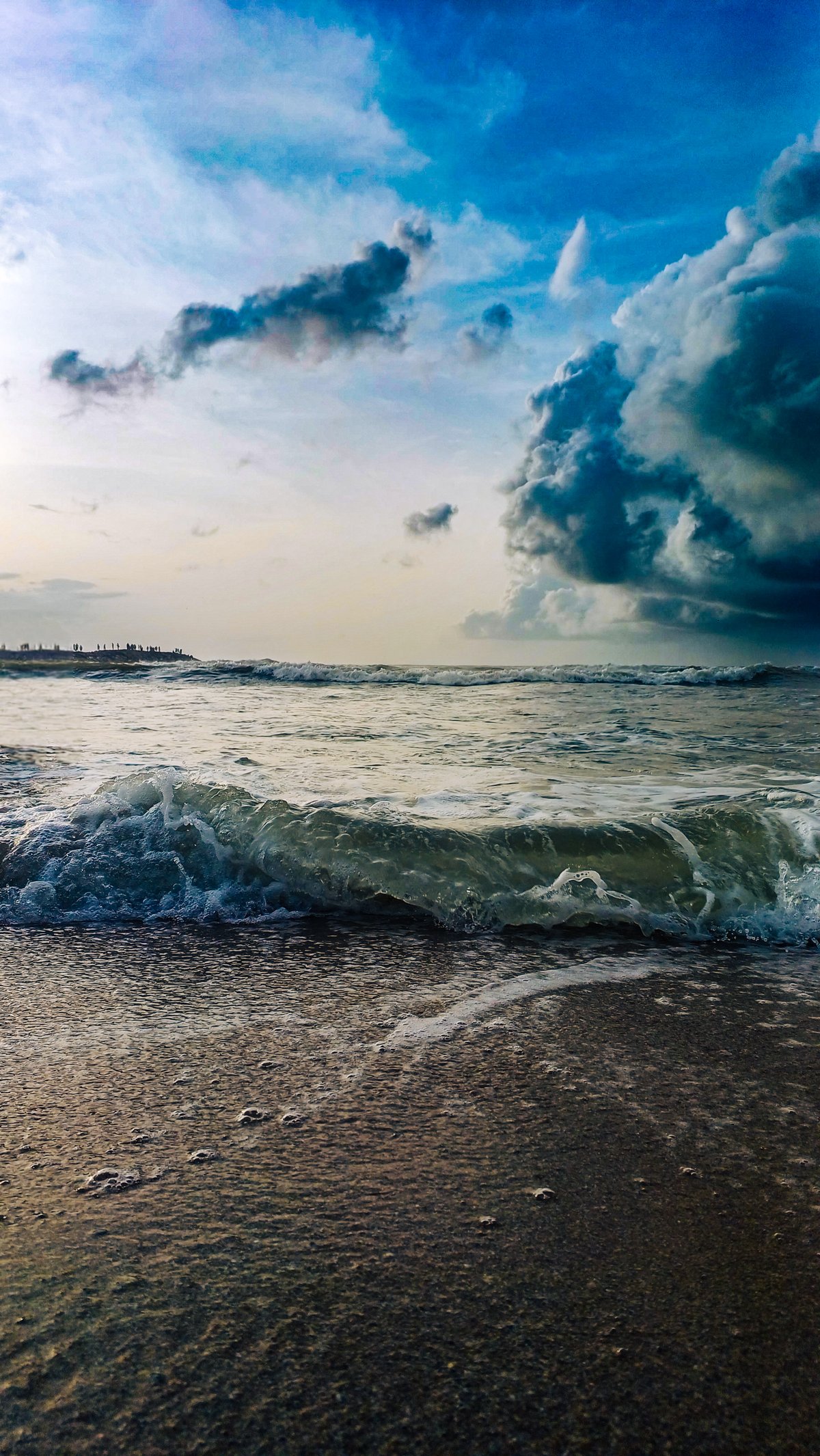 Waves meeting the horizon at Kanyakumari beach with a serene sky