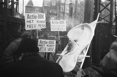 Black and white photo of BBK members demonstrating with petrol bombs and signs at the first pile driving ceremony for the Rijksmuseum Vincent van Gogh in Amsterdam, 1969