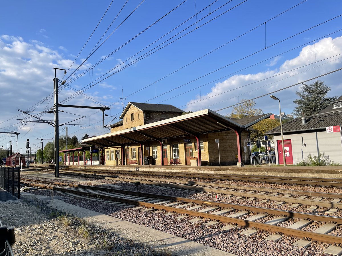 Dommeldange train station platform with train tracks and overhead electrical wires