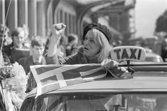 Melina Mercouri arriving at Amsterdam Central Station wearing a beret and holding a Greek flag on May 14, 1968