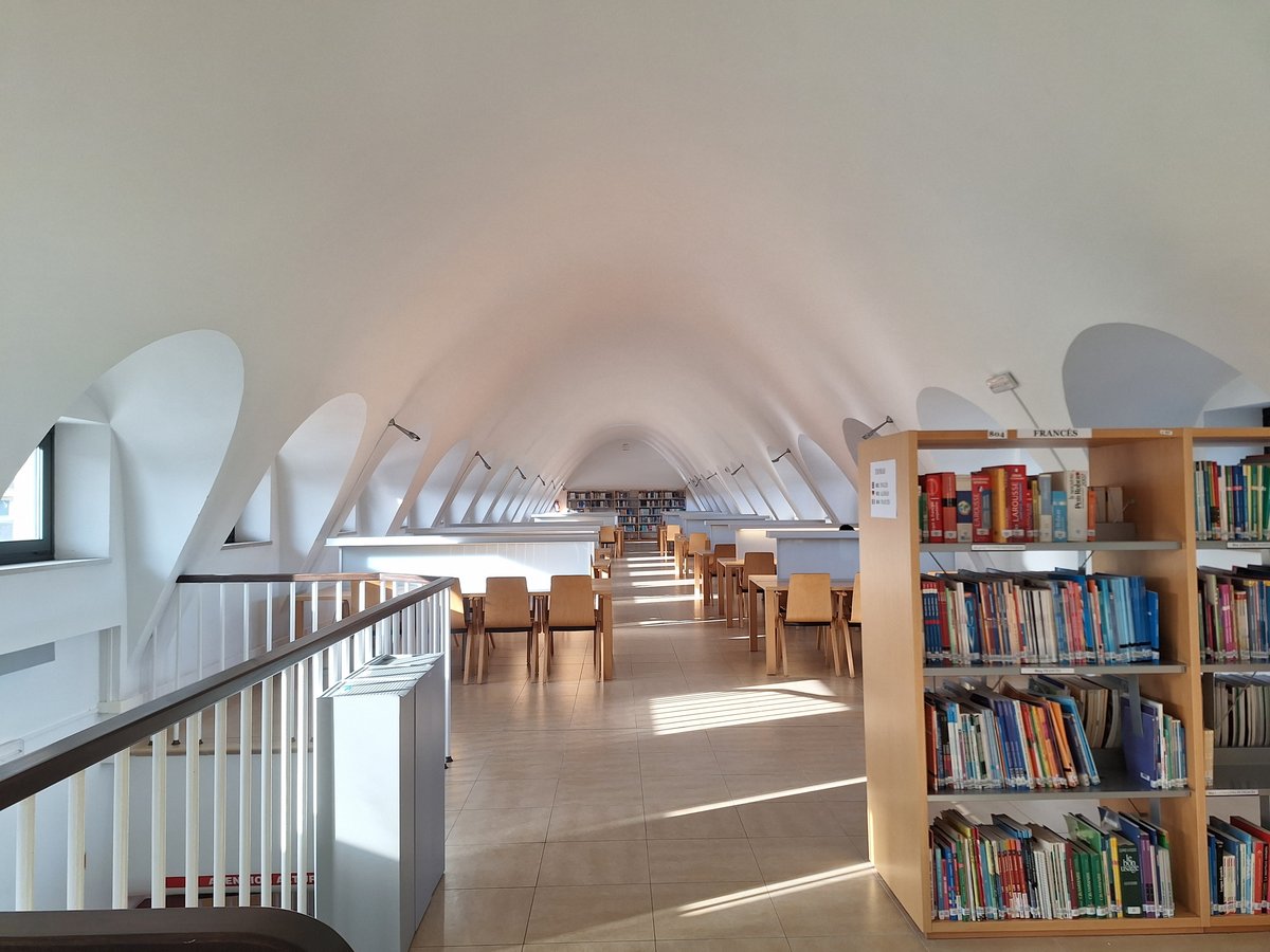 Library interior of the Faculty of Commerce, Tourism and Social Sciences Jovellanos at Universidad Laboral de Gijón with wooden bookshelves and large windows