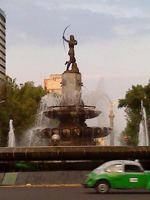 Ecologic Volkswagen Beetle Taxi in front of Diana Cazadora with Angel de la Independencia in background on Paseo de la Reforma, Mexico City