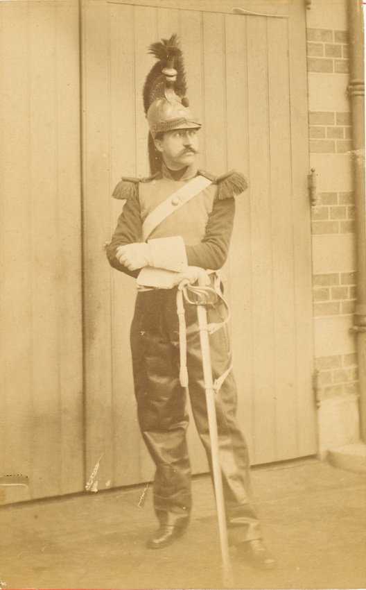 Portrait of military painter Edouard Detaille in cuirassier uniform with plume helmet and sword