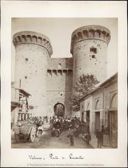 1888 street scene with people, cars, children and Quart Towers with guard at entrance