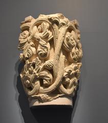 Intricately carved stone capital with intertwined vine motifs at Musée Saint Rémi Reims