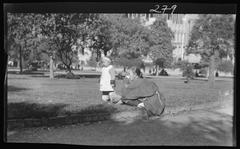 A picnic on Portsmouth Square in Chinatown, San Francisco with people gathered on grass, historical black and white photo