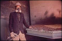 Worker wearing respiratory protection mask while spray painting at Avondale Shipyard
