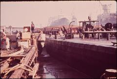 Scum and sludge polluting water at Avondale Shipyard with industrial buildings and smokestacks