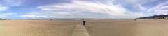 Panoramic view of Castelldefels beach with sandy shore, gentle waves, and clear horizon over the sea