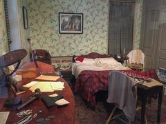 Bedroom area with bed, tables, chairs, and personal items at Thaddeus Kosciuszko National Memorial in Pennsylvania
